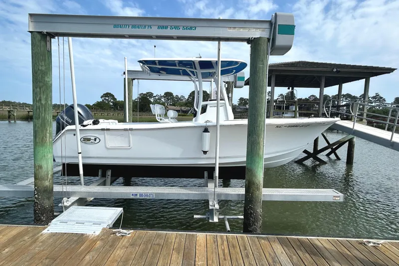 Slide: The Image of 2017 Sea Hunt Ultra 235 SE boat on lift at dockside, under clear sky. - 2