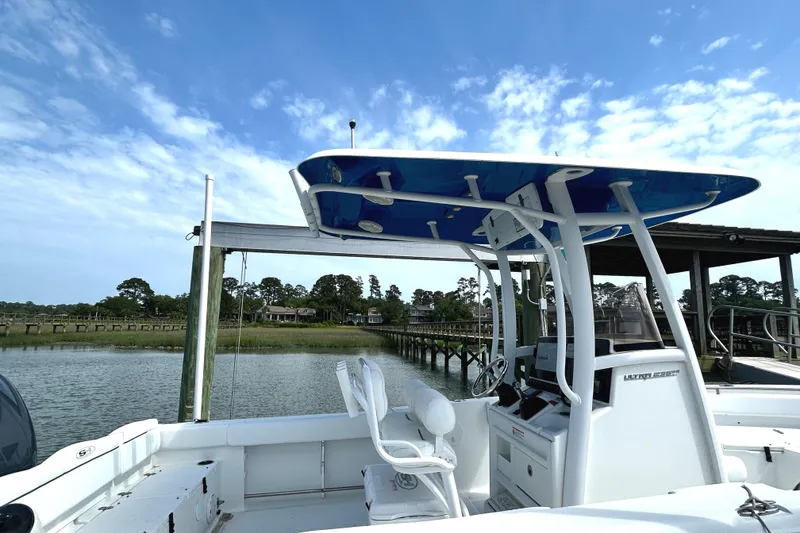 Slide: The Image of 2017 Sea Hunt Ultra 235 SE boat docked by a scenic waterfront under a clear blue sky. - 4