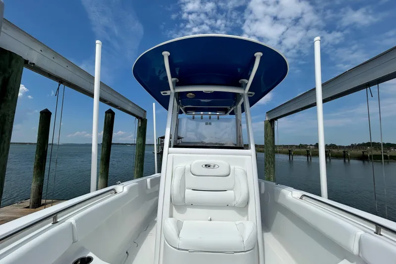 Slide: The Image of 2017 Sea Hunt Ultra 235 SE boat docked, featuring a blue T-top and white seating. - 7