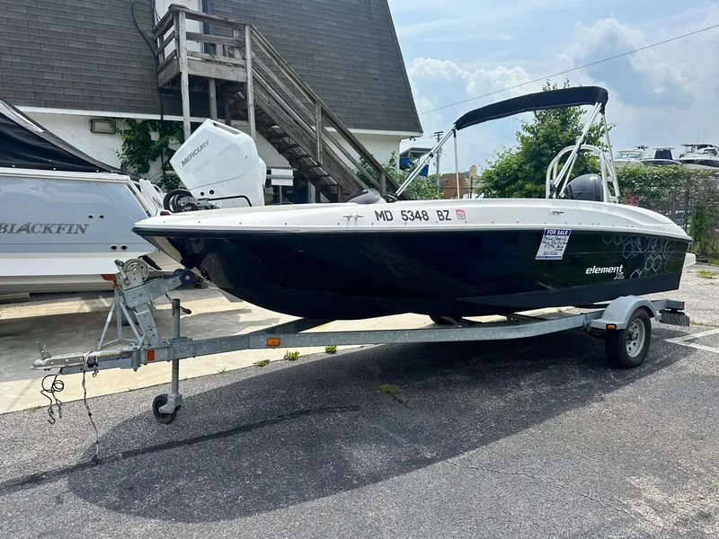 Slide: The Image of 2015 Bayliner Element E180 boat on trailer, parked outdoors near building. - 0