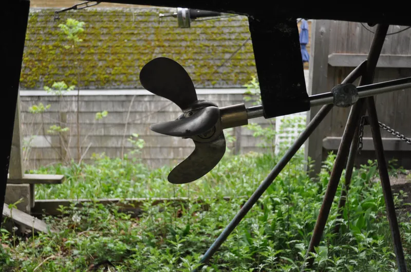 Slide: The Image of Propeller of 1984 Catalina 36 Tall Rig sailboat on a stand, surrounded by greenery. - 16