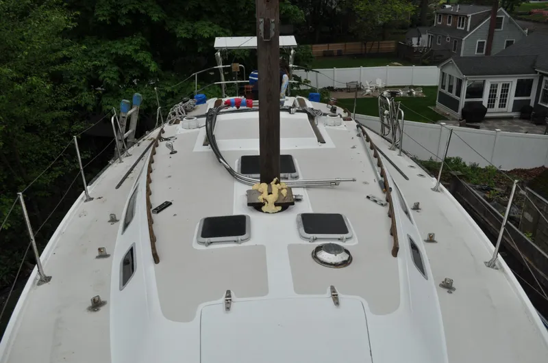 Slide: The Image of 1984 Catalina 36 Tall Rig sailboat deck, featuring hatches and rigging, surrounded by greenery and houses. - 18