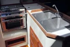 Slide: The Image of 1984 Catalina 36 Tall Rig yacht kitchen with stove, sink, and wooden cabinetry. - 7