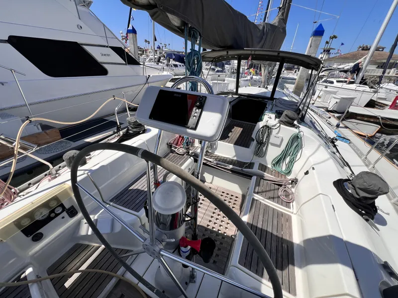 Slide: The Image of Cockpit of a 1990 Beneteau First 41s5 sailboat, featuring steering wheel and navigation equipment. - 20