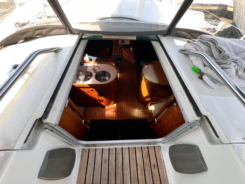 Slide: The Image of Interior view of 1990 Beneteau First 41s5 sailboat, featuring wooden flooring and compact kitchen area. - 25
