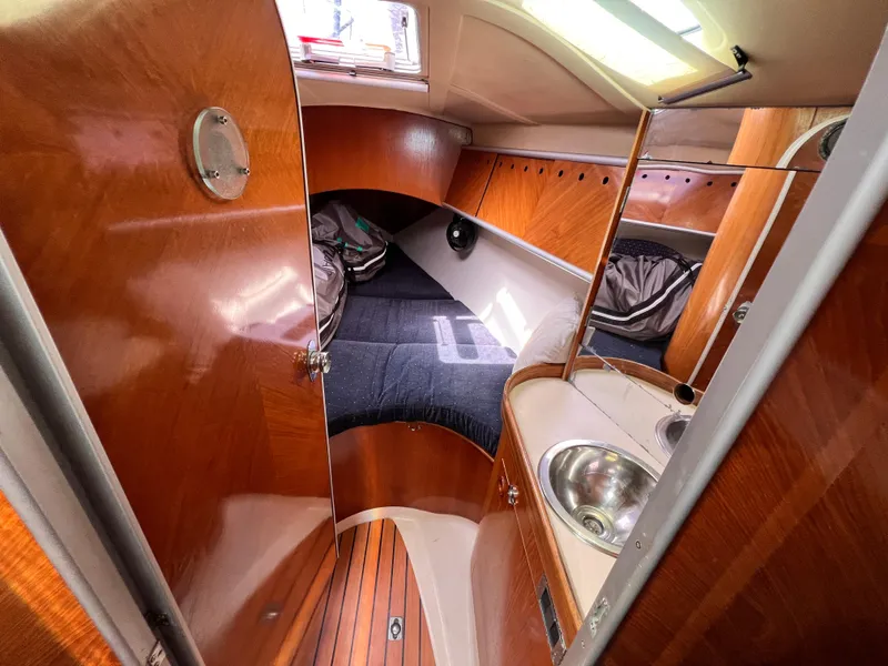 Slide: The Image of 1990 Beneteau First 41s5 yacht cabin with wood paneling and compact sink. - 29