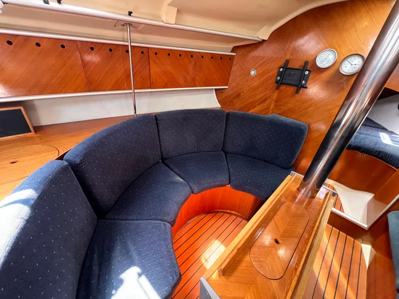 Slide: The Image of Interior of 1990 Beneteau First 41s5 yacht with curved seating and wooden finish. - 40