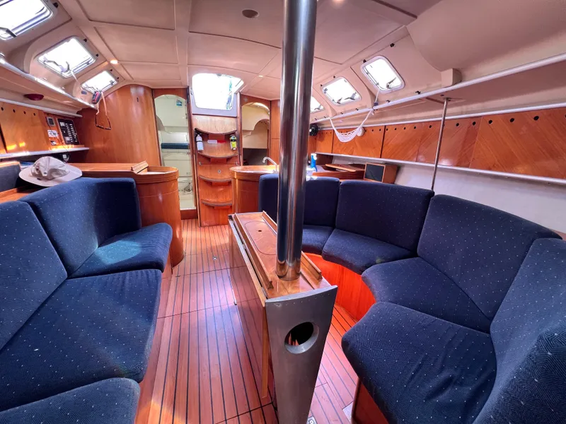 Slide: The Image of Interior of 1990 Beneteau First 41s5 sailboat with blue seating and wooden finishes. - 49