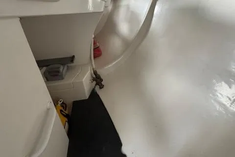 Slide: The Image of Interior of a 1985 Farr PERFORMANCE boat, featuring white surfaces and storage compartments. - 27