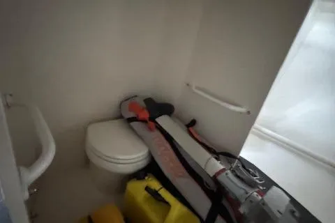 Slide: The Image of Small boat bathroom with equipment storage, featuring a toilet and various gear. - 29