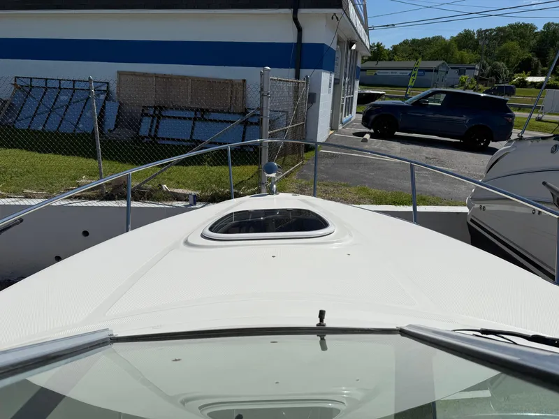 Slide: The Image of 2009 Sea Ray 230 Sundancer boat docked near a building and parked vehicles. - 16