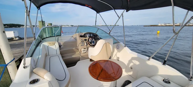Slide: The Image of 2009 Sea Ray 230 Sundancer boat interior with seating and steering, docked by the water. - 5