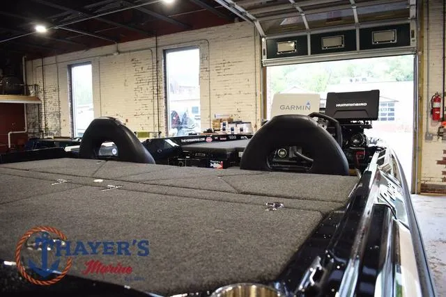 Slide: The Image of 2023 Bass Cat Puma STS boat interior with carpeted deck and dual seats in a showroom. - 17