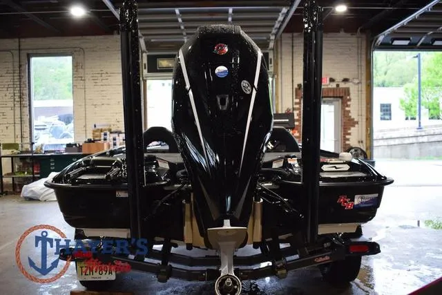 Slide: The Image of 2023 Bass Cat Puma STS boat in a garage, rear view with motor and trailer. - 8