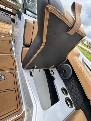 Slide: The Image of 2025 Cobalt R6 Surf boat interior with tan seating, cup holders, and speaker. - 18