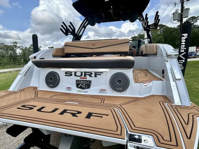 Slide: The Image of 2025 Cobalt R6 Surf boat with tan deck, speakers, and sleek design. - 9