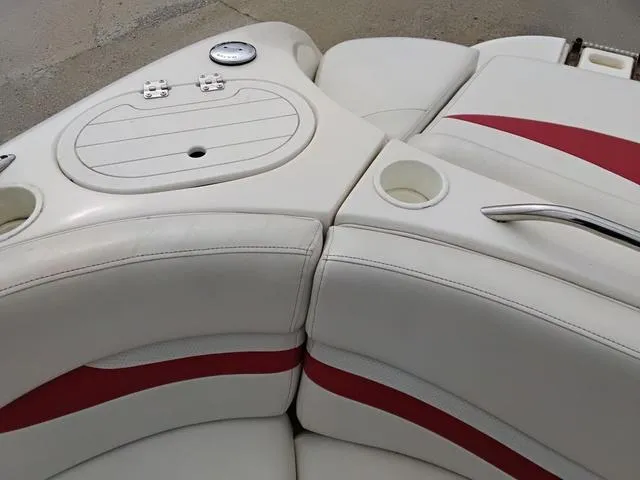 Slide: The Image of 2004 Sylvan 2240 Deck Boat interior with white and red seating, cup holders, and storage compartment. - 12