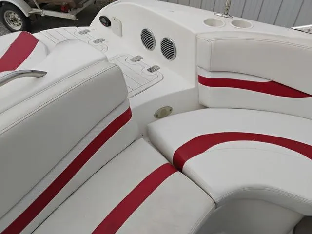 Slide: The Image of 2004 Sylvan 2240 Deck Boat interior with white and red seating, cup holders, and speakers. - 14
