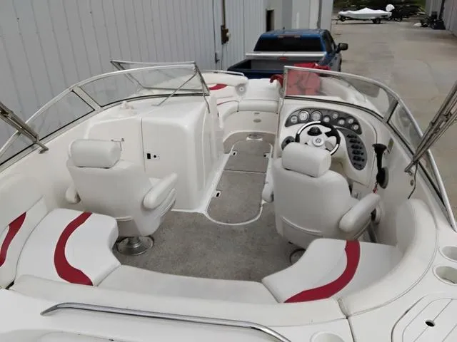 Slide: The Image of 2004 Sylvan 2240 Deck Boat interior with white and red seating, steering console, and spacious layout. - 17