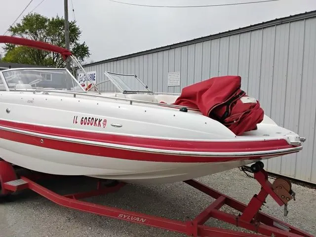 Slide: The Image of 2004 Sylvan 2240 Deck Boat with red accents on a trailer. - 3
