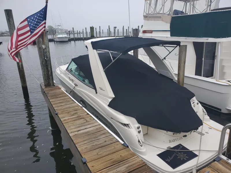 Slide: The Image of 2011 Monterey 260 SCR boat docked with American flag, covered in black canvas. - 21