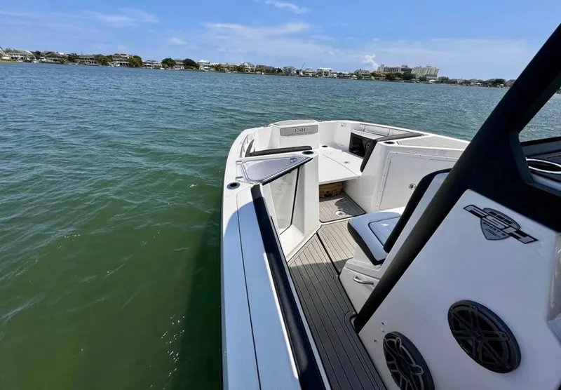 Slide: The Image of 2023 Yamaha Boats 255 FSH Sport E on calm water, showcasing sleek design and spacious deck. - 13