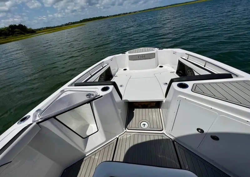 Slide: The Image of 2023 Yamaha Boats 255 FSH Sport E on water, showcasing sleek deck design and spacious layout. - 14