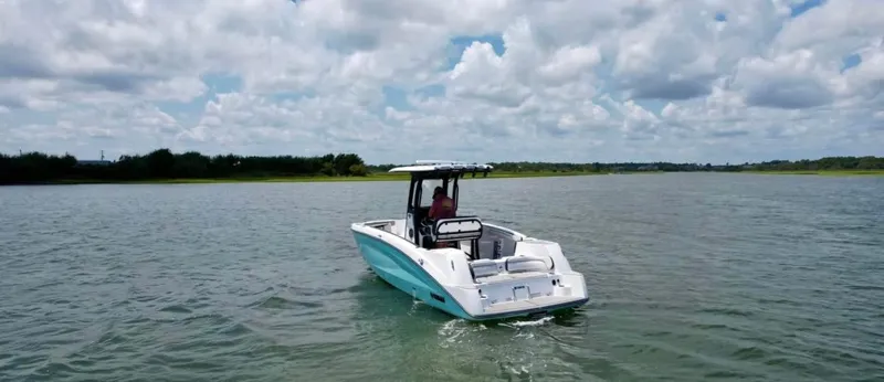 Slide: The Image of 2023 Yamaha Boats 255 FSH Sport E on a serene lake under cloudy skies. - 7