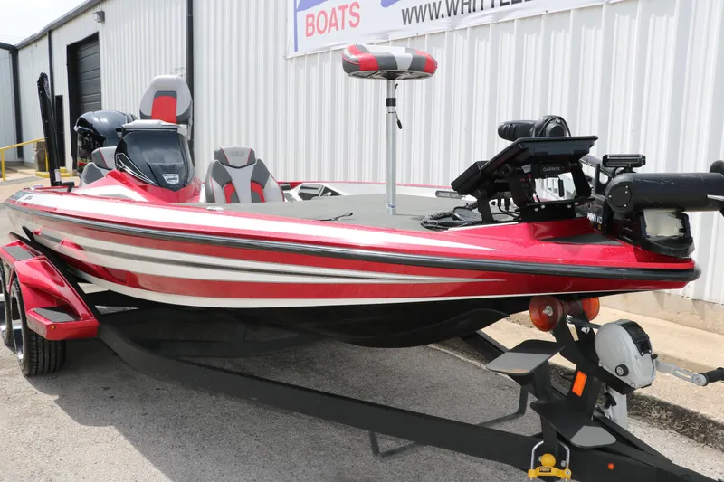 Slide: The Image of 2019 Skeeter FX20 bass boat, red and white, parked on a trailer. - 10