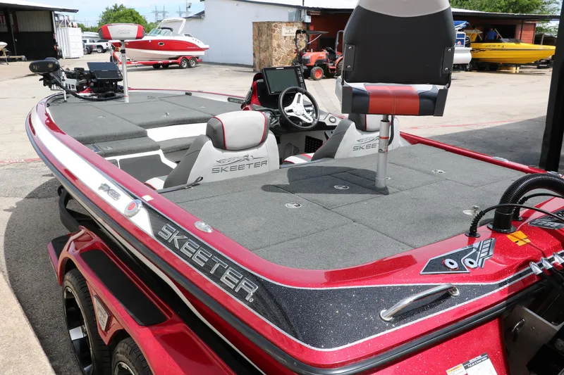 Slide: The Image of 2019 Skeeter FX20 bass boat with red and gray detailing, parked outdoors. - 7
