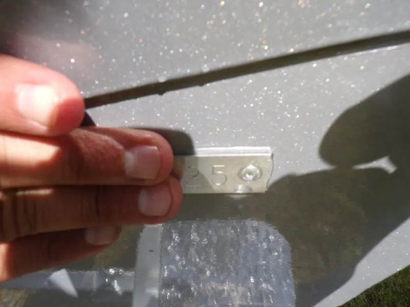 Slide: The Image of Hand holding a metal plate on a 2025 Xpress H20BAY boat hull. - 2