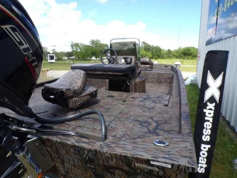 Slide: The Image of 2025 Xpress XP20CC boat with camouflage design and outboard motor, parked outdoors. - 9