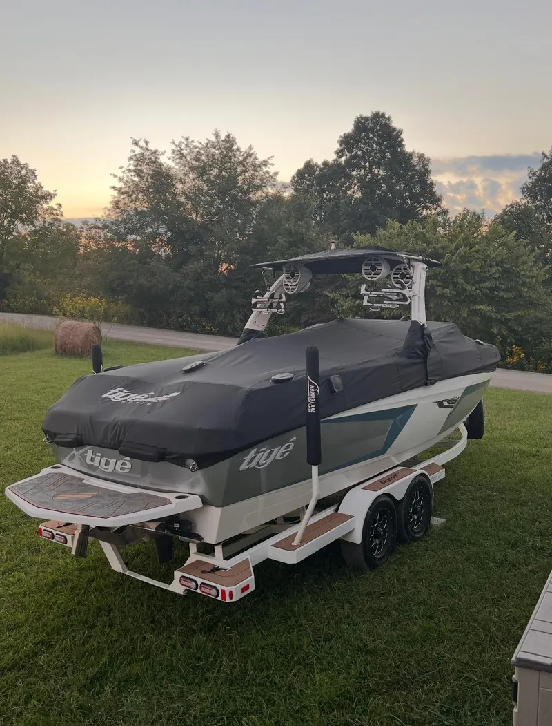 Slide: The Image of 2022 Tigé 24RZX boat on trailer, covered, parked on grass at sunset. - 10