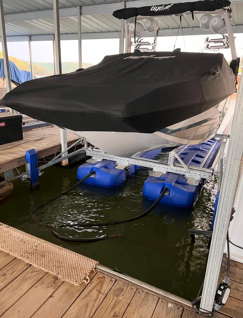 Slide: The Image of 2022 Tigé 24RZX boat on lift, covered, in docked position. - 13