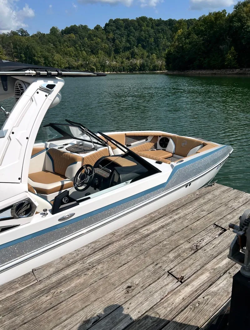 Slide: The Image of 2022 Tigé 24RZX boat docked on a serene lake with lush green surroundings. - 4
