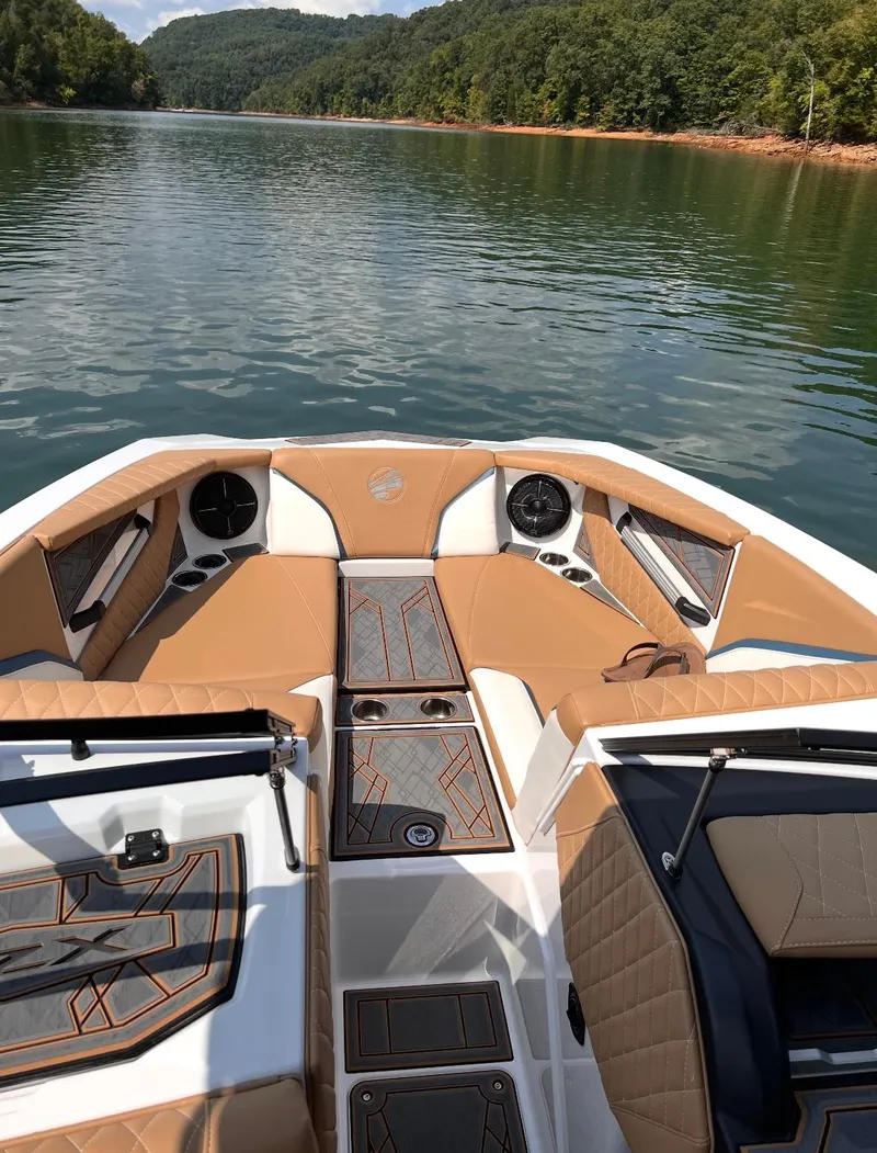 Slide: The Image of 2022 Tigé 24RZX boat interior on a serene lake with lush green surroundings. - 7