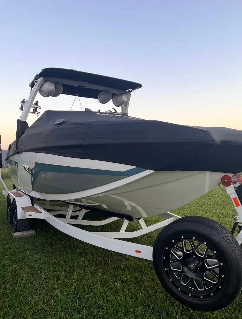 Slide: The Image of 2022 Tigé 24RZX boat on trailer, covered, parked on grass at sunset. - 9