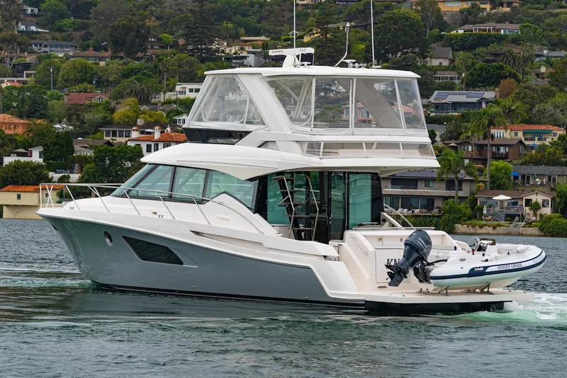 Slide: The Image of 2019 Tiara Yachts F 53 cruising on a scenic waterfront with lush greenery. - 2