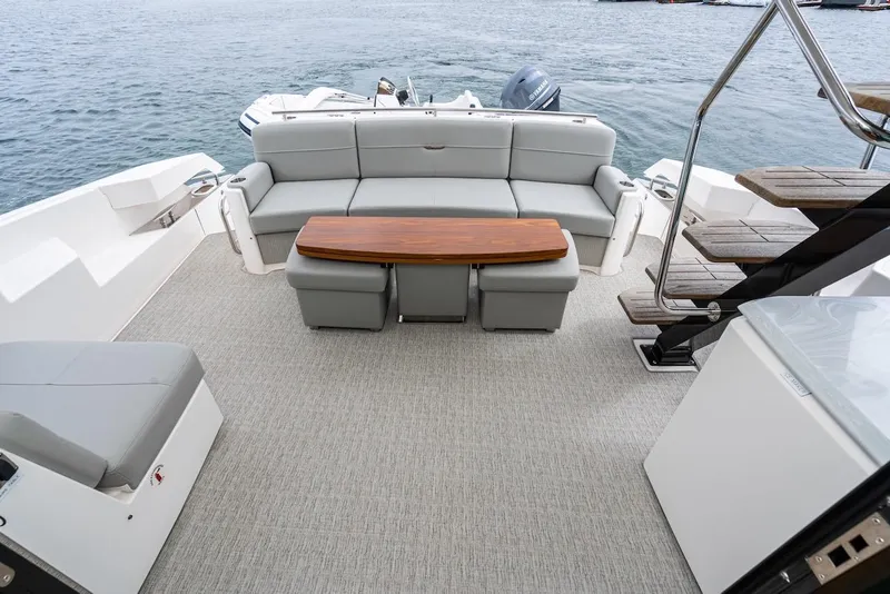 Slide: The Image of 2019 Tiara Yachts F 53 deck with seating, table, and stairs by the water. - 30