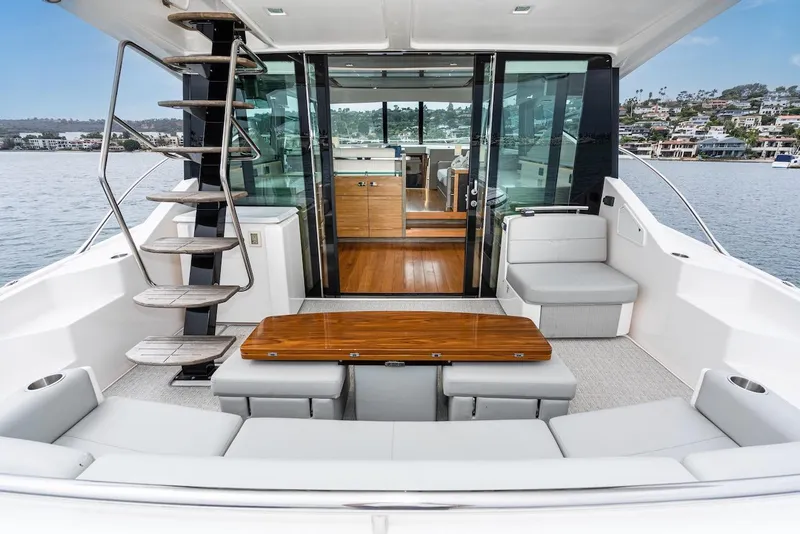 Slide: The Image of 2019 Tiara Yachts F 53 interior with seating, table, and staircase on a calm waterfront. - 36