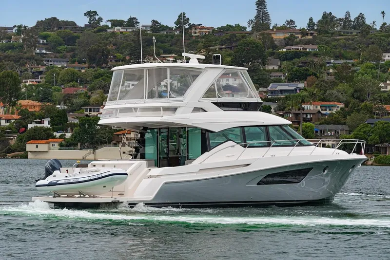 Slide: The Image of 2019 Tiara Yachts F 53 cruising on a scenic lake with hillside homes in the background. - 4
