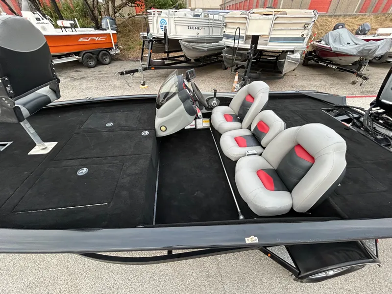 Slide: The Image of 2016 Tracker Pro Team 175 TXW boat with gray and red seating, parked outdoors. - 13