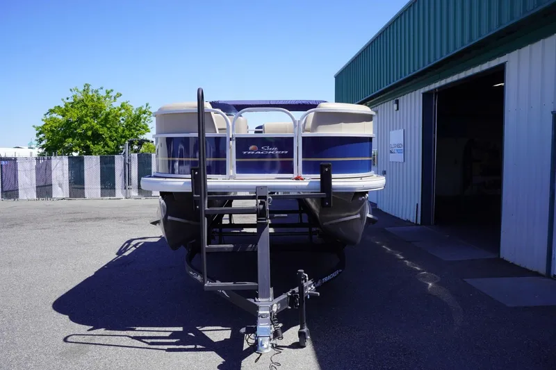 Slide: The Image of 2022 Sun Tracker Party Barge 18 DLX pontoon boat on trailer outside a warehouse. - 3