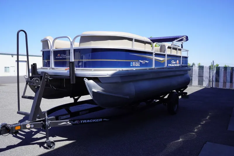Slide: The Image of 2022 Sun Tracker Party Barge 18 DLX pontoon boat on trailer, parked outdoors. - 4