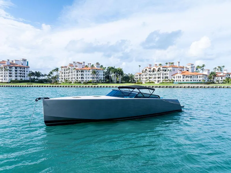 Slide: The Image of VanDutch 55 yacht from 2015 on turquoise water, with luxury waterfront buildings in the background. - 2