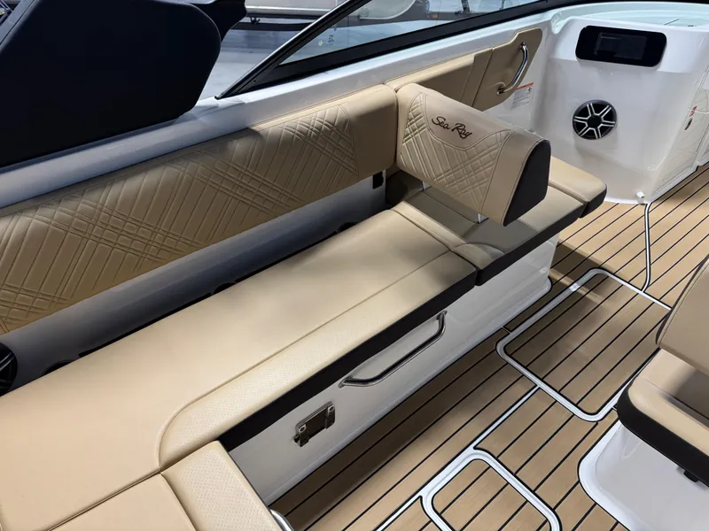 Slide: The Image of 2026 Sea Ray SDX 250 Surf boat interior with beige seating and teak flooring. - 11