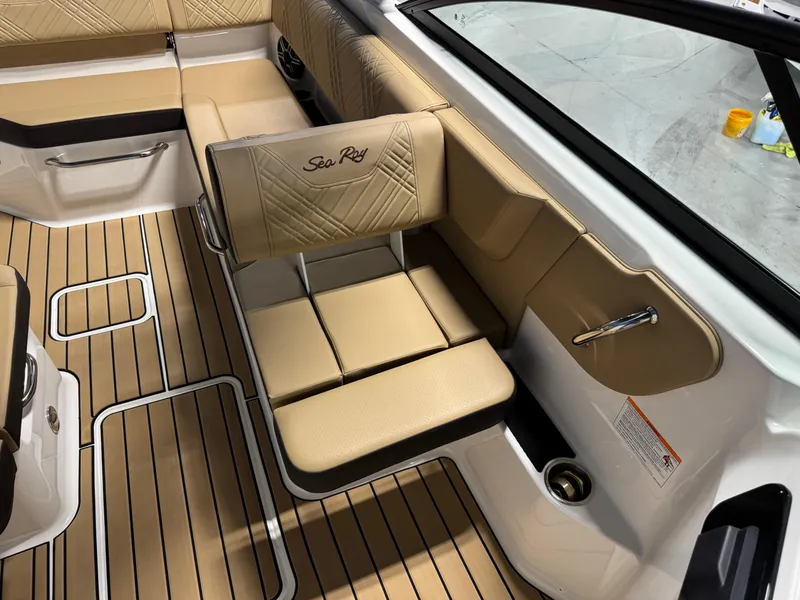 Slide: The Image of 2026 Sea Ray SDX 250 Surf boat interior with tan seating and teak flooring. - 12