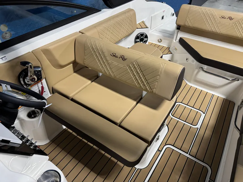 Slide: The Image of 2026 Sea Ray SDX 250 Surf boat interior with tan seating and wood-style flooring. - 13