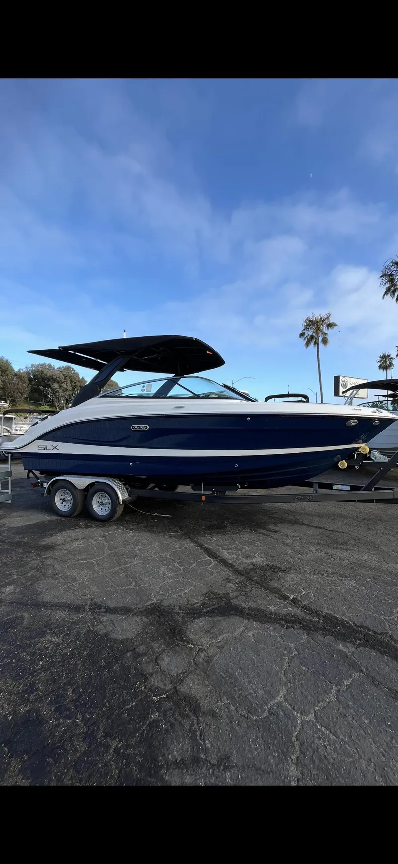 The Image of 2026 Sea Ray SLX 260 boat on trailer, parked outdoors under blue sky. - 0