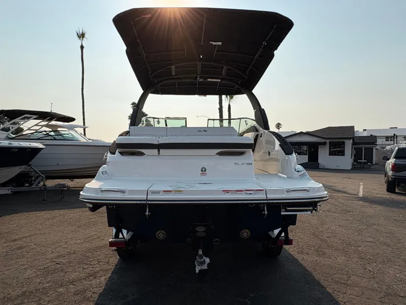 Slide: The Image of 2026 Sea Ray SLX 260 boat, rear view, parked outdoors under a clear sky. - 3